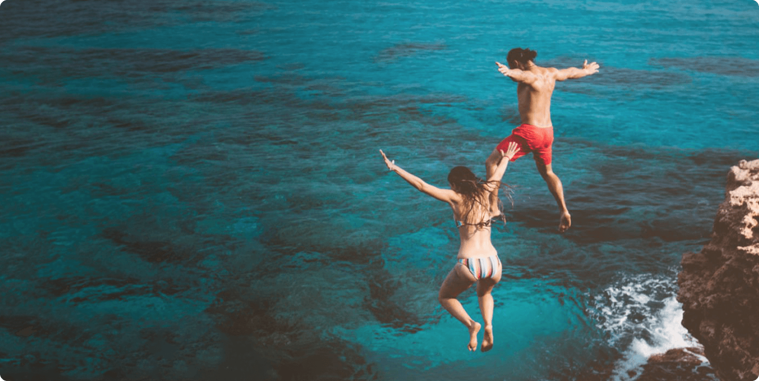 Theta Wave brand “About Us” image – two people jumping into clear blue water symbolizing flow, clarity and natural wellness